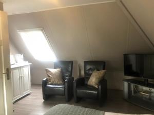 two black chairs and a television in a room at De Tuinkamer in Ter Apel