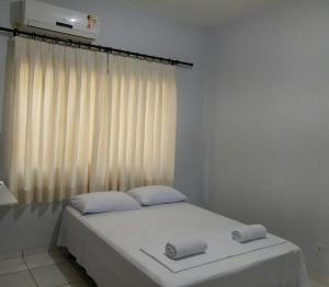 a bedroom with a bed with white sheets and a window at Pousada Braga in Palmas