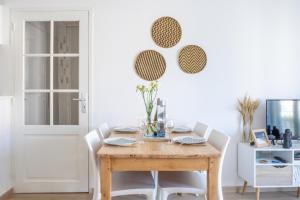uma sala de jantar com uma mesa de madeira e cadeiras brancas em Le Coton em Saint Malo
