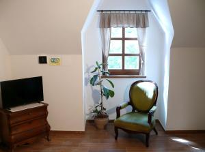 Habitación con silla, TV y ventana en Kádárta Vendéglő Panzió, en Veszprém