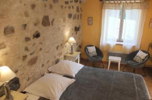 a bedroom with two chairs and a bed at La Pierre Folle Chambres d'Hôtes in Cluny