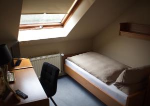 a small room with a bed and a desk and a window at Hotel Landhaus Steinhoff in Rheinberg