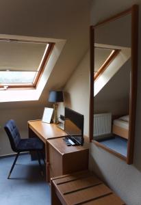 a room with a desk with a computer and a mirror at Hotel Landhaus Steinhoff in Rheinberg