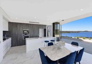 a kitchen with a dining table and a view of the water at Stylish Penthouse with Views & Jacuzzi in Gosford