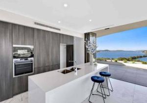 a kitchen with a counter with stools and a view of the ocean at Stylish Penthouse with Views & Jacuzzi in Gosford