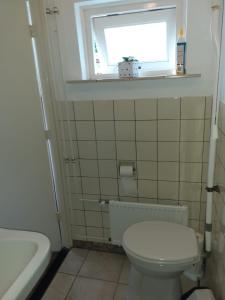 uma casa de banho com um WC branco e uma janela em Vakantiehuisje in Centrum Ootmarsum em Ootmarsum