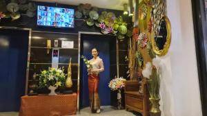 une femme debout devant un miroir tenant des fleurs dans l'établissement SUDYOD HOTEL, à Ban Bang Bamru