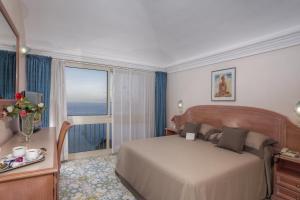 a hotel room with a bed and a large window at Le Querce Resort Sea Thermae & Spa in Ischia