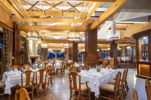a dining room with tables and chairs and chandeliers at Pirin Golf Hotel & Spa in Bansko