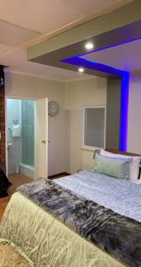 um quarto com uma cama grande e uma luz azul em Made Guest House em Joanesburgo