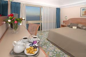 a hotel room with a bed and a table with a tray of food at Le Querce Resort Sea Thermae & Spa in Ischia