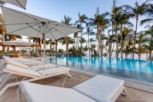 a pool with chairs and umbrellas and palm trees at Hotel Fariones in Puerto del Carmen