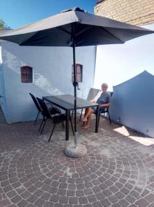 Un uomo seduto a un tavolo sotto un ombrello di Rødby Købstadshotel a Rødby