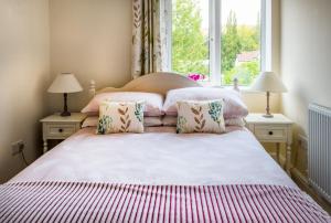 a bedroom with a bed with two lamps and a window at Magnolia Cottage in Church Stretton