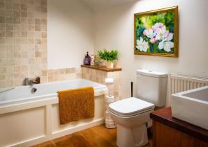 a bathroom with a tub and a toilet and a sink at Magnolia Cottage in Church Stretton +51 photos