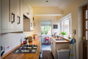 uma cozinha com armários brancos e um forno com placa de fogão em Magnolia Cottage em Church Stretton