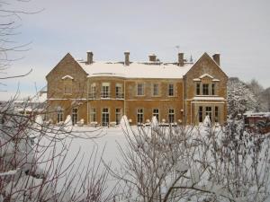 a large brick house with snow on its roof at Wyck Hill House Hotel & Spa in Stow on the Wold