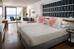 a bedroom with a large white bed and a living room at Hotel Fariones in Puerto del Carmen
