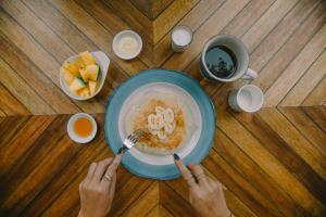 a person eating a bowl of cereal with a bowl of fruit at SANSE Boutique Hotel in El Nido