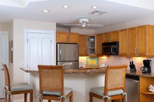 a kitchen with wooden cabinets and a counter with chairs at Villa Renaissance Unit 501 Grace Bay Beach in The Bight Settlements