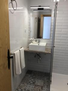 Baño blanco con lavabo y espejo en Hotel Finca Alcamino en Mompía