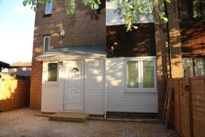 a white garage with a door on the side of a house at Budget 4-Bedrooms In Thamesmead in London