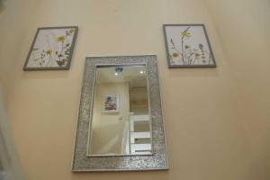 a mirror hanging on a wall with three pictures at Budget 4-Bedrooms In Thamesmead in London