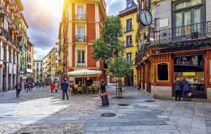 un grupo de personas caminando por una calle de la ciudad con un reloj en Cálamo Guesthouse, en Madrid
