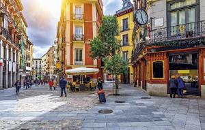 a group of people walking down a city street with a clock at Cálamo Guesthouse in Madrid