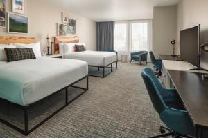 a hotel room with two beds and a desk and chairs at The Independence Hotel in Independence