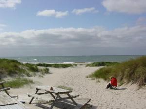 eine Person, die am Strand in der Nähe eines Picknicktisches sitzt in der Unterkunft Rødby Købstadshotel in Rødby