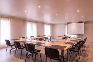 a conference room with tables and chairs and a screen at The Originals Boutique, Parc Hôtel, Orléans Sud in La Chapelle-Saint-Mesmin