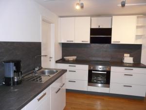 a kitchen with white cabinets and a sink at Ferienwohnung Kampenwand-Loft in Aschau im Chiemgau