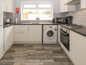 a kitchen with white cabinets and a washer and dryer at Ty Haf Summerhouse in Prestatyn