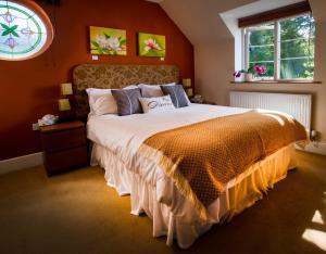 a bedroom with a large bed with an orange wall at Berries Coach House in Church Stretton