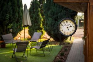 a clock hanging on the side of a yard with chairs at MBL Apartments Autumn in Rezi