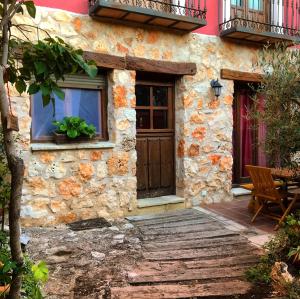 une maison en pierre avec une porte en bois et une table dans l'établissement La Noguera de Socasa, à Romancos