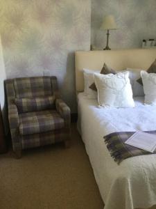 um quarto de hotel com duas camas e uma cadeira em Glenspean Lodge Hotel em Roybridge