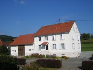 une grande maison blanche avec un toit rouge dans l'établissement Gîte Léonline sur les hauteurs de Masevaux -au pied des Vosges, à Masevaux