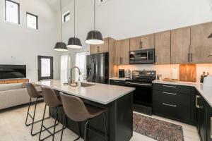 a kitchen with black cabinets and a kitchen island with chairs at Burnett Cottage - OG in Cedar Rapids