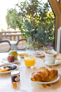 - une table avec des assiettes de produits pour le petit-déjeuner et du jus d'orange dans l'établissement Hôtel Saint-Hubert, à Saint-Claude