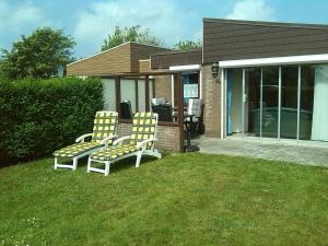 zwei Stühle auf einem Rasen vor einem Haus in der Unterkunft Vacation home Zwaantje #BL66 in Callantsoog
