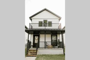 a white house with a porch and a balcony at Burnett Cottage - Pine in Cedar Rapids