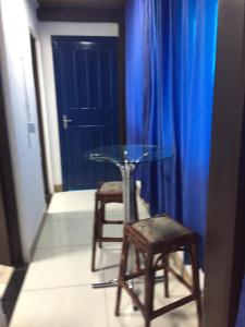 una mesa de cristal y 2 sillas y una cortina azul en Pousada Alessandra, en Bombinhas