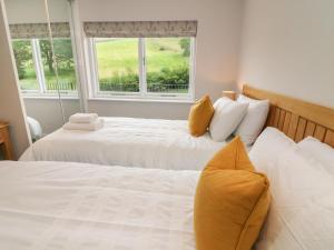 two beds in a room with two windows at Beck View in Kendal