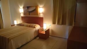 a bedroom with a bed and two lamps on tables at Chalé frente mar e frente piscina Zumbi-RN in Rio do Fogo