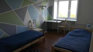 a room with two beds and a desk and a window at Central MaxiStay in Rakvere