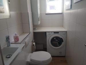 ein kleines Bad mit einer Waschmaschine und einem WC in der Unterkunft Fewo Daisy 195 in Wilhelmshaven