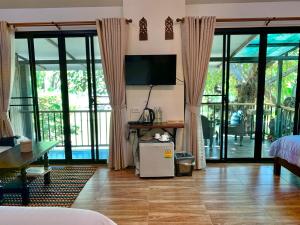 ein Wohnzimmer mit Glasschiebetüren und einem TV in der Unterkunft Nan Rim Nam Resort in Nan