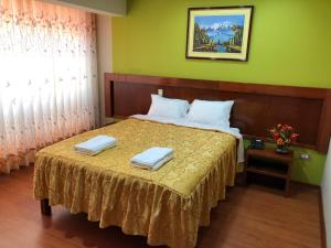 a bedroom with a bed with two towels on it at Sumaq Hotel Tacna in Tacna